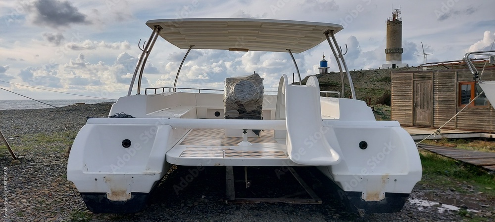 new, white plastic catamaran on the beach in the marina. new, white plastic catamaran on the beach in the marina.