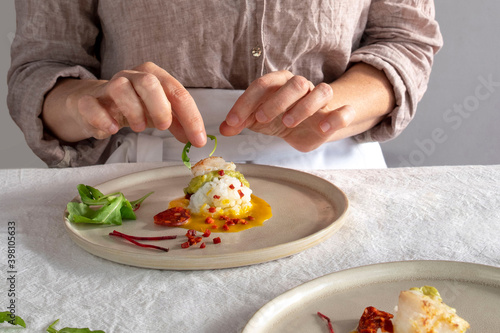 Fototapeta Naklejka Na Ścianę i Meble -  A woman prepares a gastronomic dish at home or in a restaurant