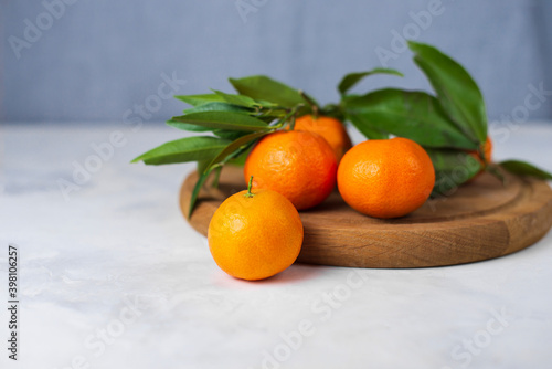 Sweet juicy orange New Year's clementine tangerines, mandarines with green leaves. Citrus still life on a light gray background. Healthy winter fruits with vitamin C for boost immunity. Copy space © Kira
