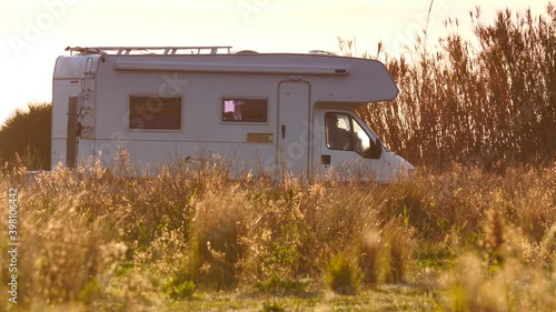 Camper, recreational vehicle camping on coastal meadow field at sunny day in Spain. Traveling by motorhome. Caravan vacation.