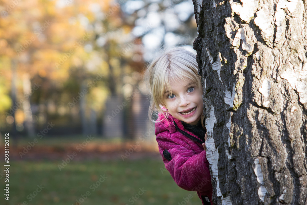 Kleines Mädchen schaut frech hinter Baum hervor Kleines Mädchen schaut frech hinter Baum hervor