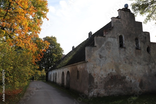 Old antique stone barn in the Latvian village of Auce among autumn trees on October 13, 2020