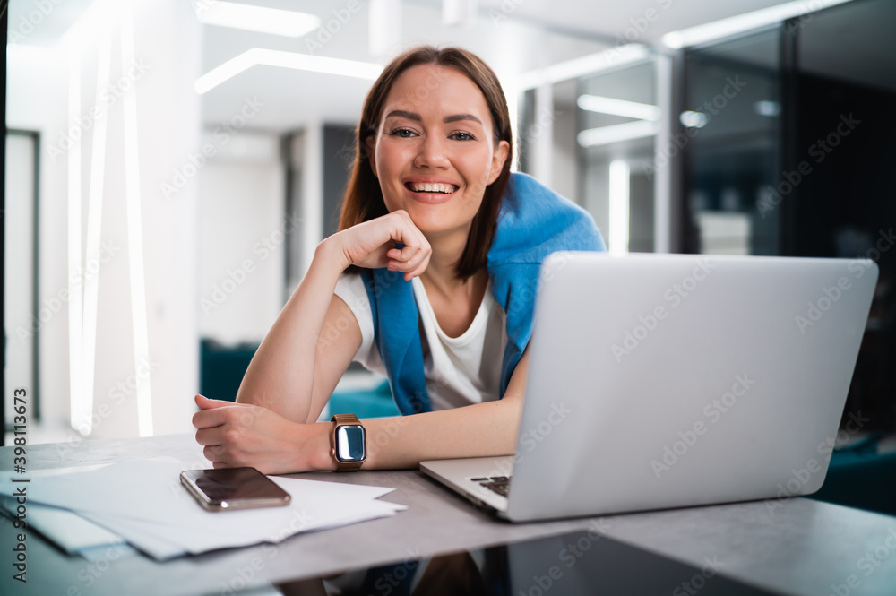 Smiling young woman blogger influencer working at home. Happy girl working remotely from home sitting at desk with laptop and smiling at camera. Smiling young woman blogger influencer working at home. Happy girl working remotely from home sitting at desk with laptop and smiling at camera.