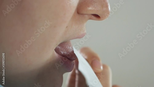 Side view of lips of young woman licking white envelope for mail