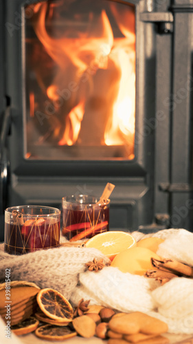 mulled wine by the fireplace, 2 glasses of drink, spices and a warm scarf by the stove