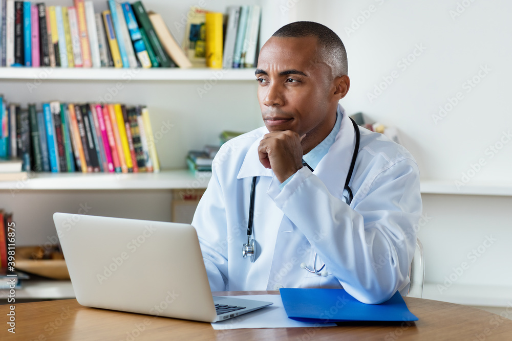 Thinking african american male doctor at computer Thinking african american male doctor at computer