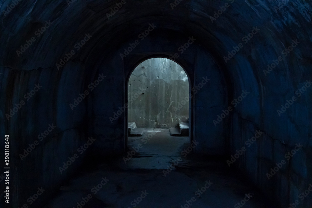 A door to freedom, illuminated by light, at the exit from a dark underground corridor glowing with a mysterious blue light.