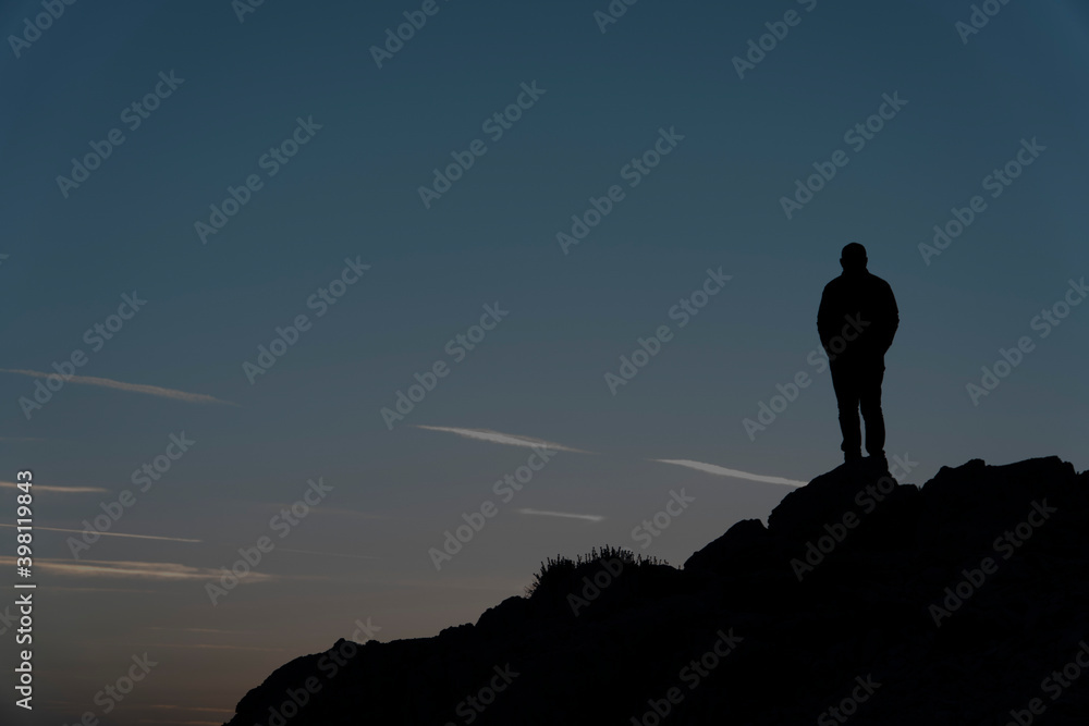 Silhouettes of man  on top of a mountain.