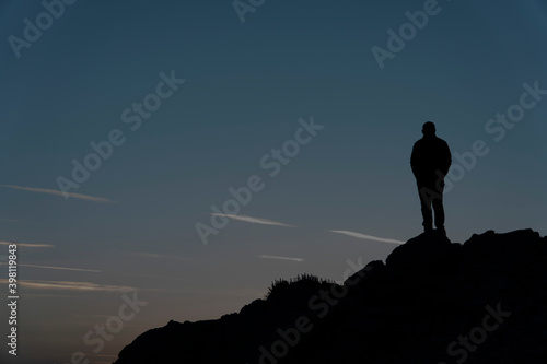Silhouettes of man on top of a mountain.
