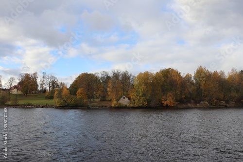 Panorama across the river to the opposite bank with yellowed autumn trees