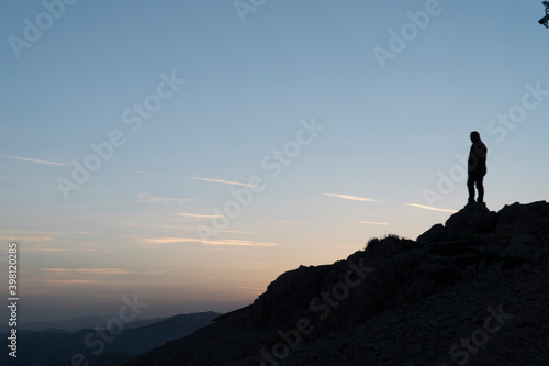 Silhouettes of man on top of a mountain.