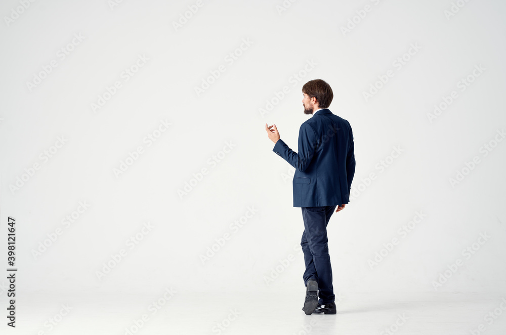 Gentleman in a blue suit gestures with his hands on a light background back view business finance Gentleman in a blue suit gestures with his hands on a light background back view business finance