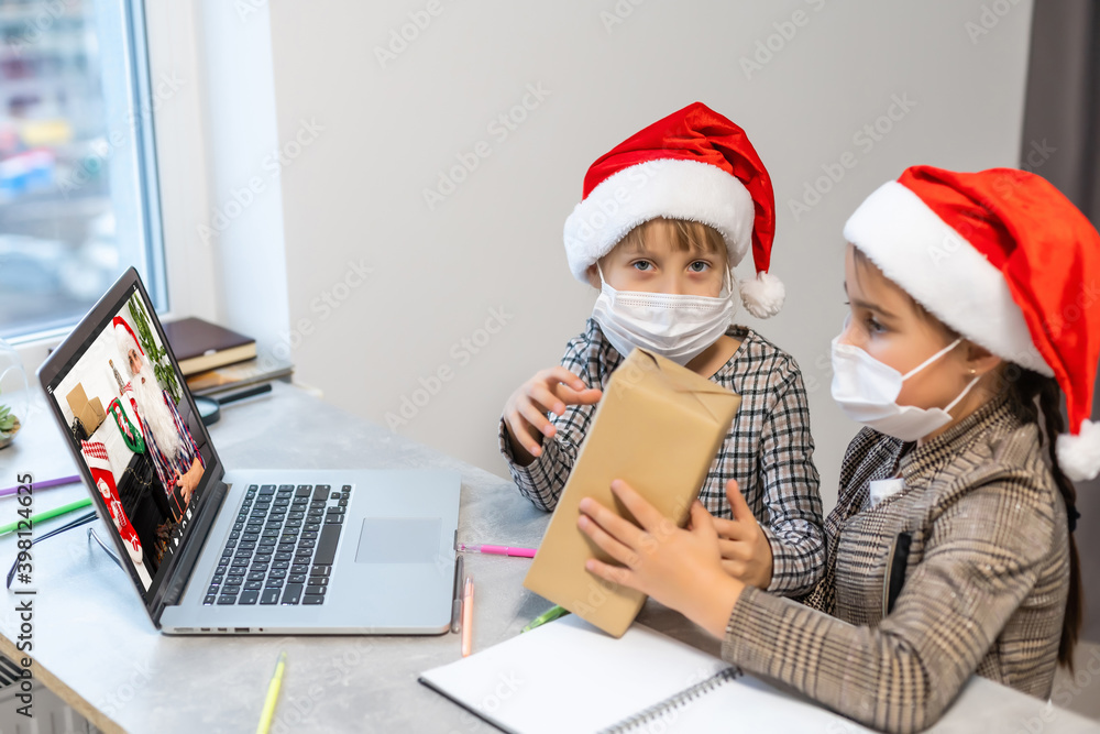 A group of children watching a video chat with Santa using a laptop in a decorated room during Christmas. girls 8-9 years talking with Santa Claus have a computer camera in a home. A group of children watching a video chat with Santa using a laptop in a decorated room during Christmas. girls 8-9 years talking with Santa Claus have a computer camera in a home.