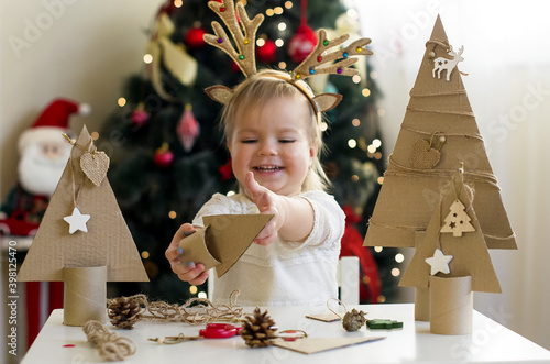 Funny child girl making decorations for christmas Handmade Christmas trees from natural materials. Concept of winter kids creativity and christmas crafts, eco friendly Christmas tree  photo