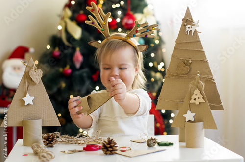 Funny child girl making decorations for christmas Handmade Christmas trees from natural materials. Concept of winter kids creativity and christmas crafts, eco friendly Christmas tree  photo