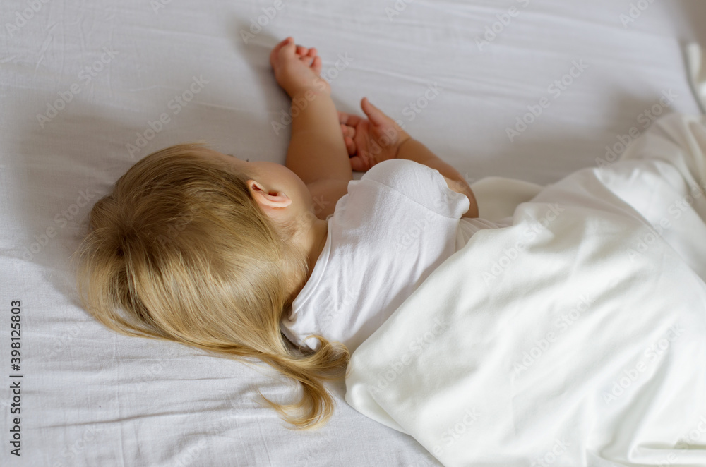 Faceless toddler girl with blonde hair sleeping on white bed. Rear view of a two year old child girl sleeping a beautiful and comfortable bed Faceless toddler girl with blonde hair sleeping on white bed. Rear view of a two year old child girl sleeping a beautiful and comfortable bed