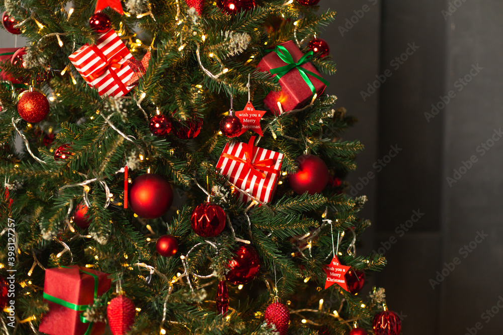 Closeup branches of coniferous tree decorated with red balls and light garland at Christmas night Closeup branches of coniferous tree decorated with red balls and light garland at Christmas night