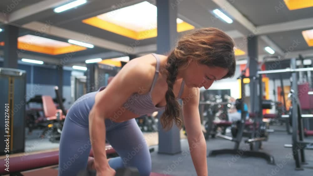 Fitness girl is exercising with in a gym. Sporty woman is lifting a weight. Fitness, body and health concept Fitness girl is exercising with in a gym. Sporty woman is lifting a weight. Fitness, body and health concept