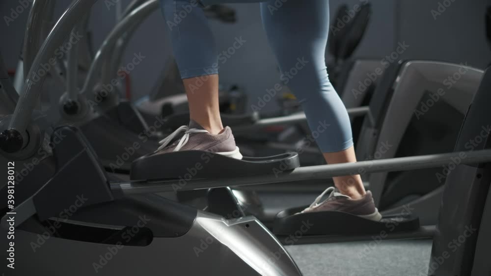 Young woman is working out on stepper in a gym. She is walking on orbitrek for cardio intensity and endurance improvement. Fit woman on cardio stepper. Fitness, body and health concept Young woman is working out on stepper in a gym. She is walking on orbitrek for cardio intensity and endurance improvement. Fit woman on cardio stepper. Fitness, body and health concept