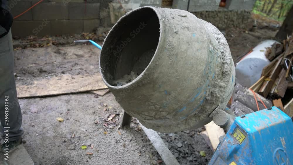 Worker shoveling gravel into a cement mixer Worker shoveling gravel into a cement mixer
