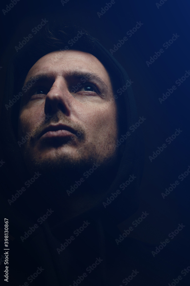 Man in a dark room in a hood Man in a dark room in a hood