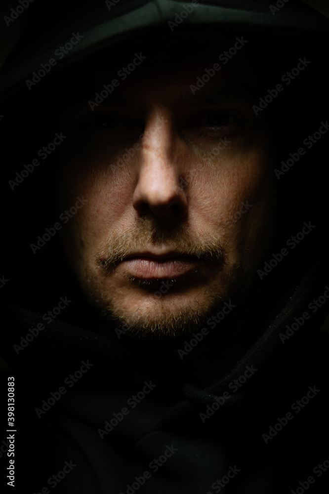 Man in a dark room in a hood Man in a dark room in a hood