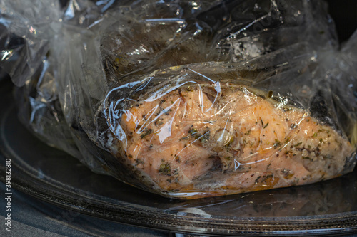 Spiced fresh trout fish wrapped in a baking sleeve in a microvawe oven, cooked, closeup view photo