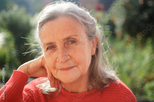 Portrait of a mature woman with grey hair spending time outdoors during sunny day, happy retirement