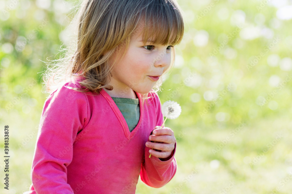 cute little girl blowing dandelion