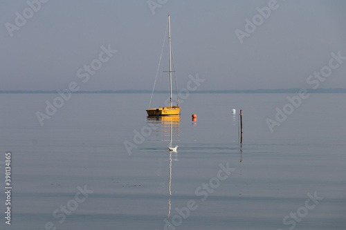 Yelow small sailing boat on the calm sea in the early morning