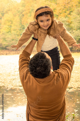 Father and daughter dressed in autumn colors are having fun. Father held his daughter in the air. little girl laughing.