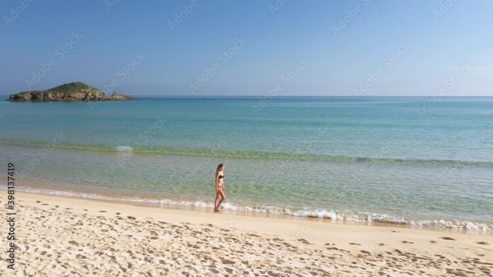 Aerial of a beautiful woman walking down a beautiful white sand beach on Sardinia, Italy Aerial of a beautiful woman walking down a beautiful white sand beach on Sardinia, Italy