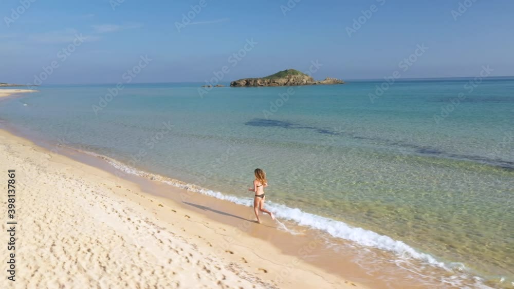 Aerial of a beautiful woman walking down a beautiful white sand beach on Sardinia, Italy Aerial of a beautiful woman walking down a beautiful white sand beach on Sardinia, Italy