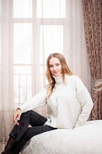 Young beautiful woman in warm knitted handmade clothes at home. 