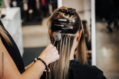 Tableau sur toile The hairdresser does hair extensions to a girl, a blonde in a beauty salon