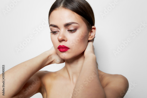 Woman holding hands behind head red lips bare shoulders studio cropped view 