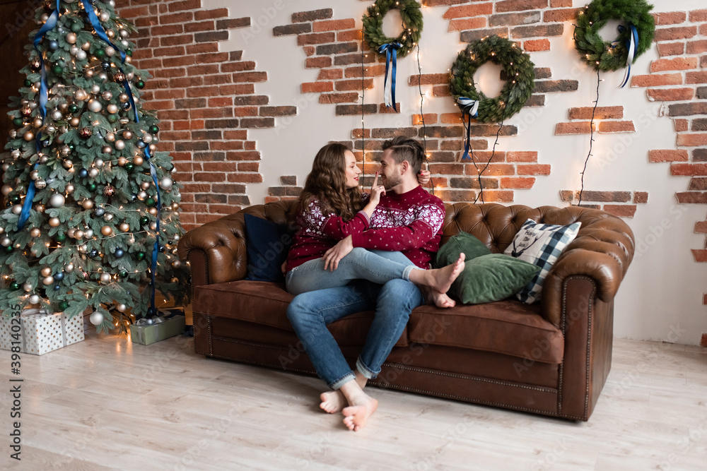 Obraz premium Husband and wife in identical knitted sweaters have fun together celebrating Christmas.