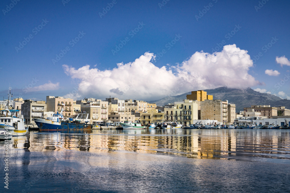 Panoramic view of the old town from the fishing port with the reflection of boats, water and clouds in the sky.