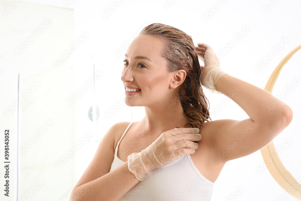 Young woman applying dye on hairs in bathroom Young woman applying dye on hairs in bathroom