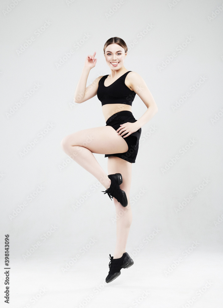 Full length portrait of a young fitness woman in sportswear posing and jumping isolated over gray background Full length portrait of a young fitness woman in sportswear posing and jumping isolated over gray background