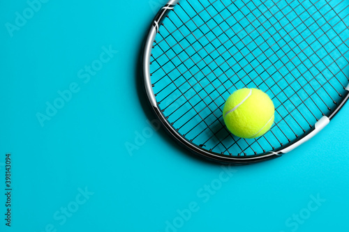 Tennis racket and ball on blue background, top view. Space for text © New Africa
