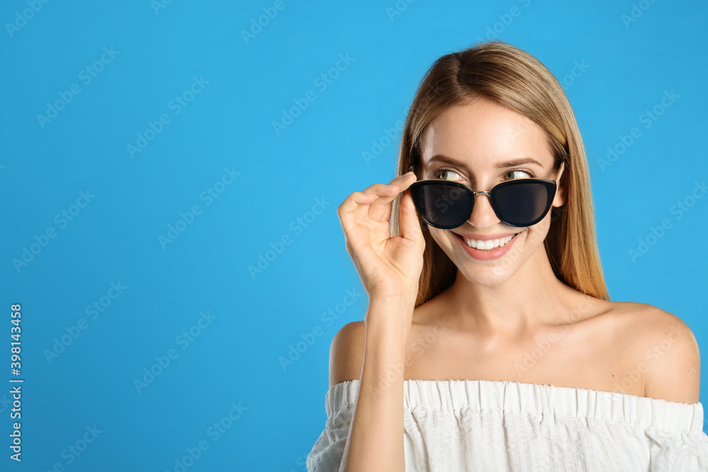Beautiful woman in stylish sunglasses on light blue background, space for text Beautiful woman in stylish sunglasses on light blue background, space for text