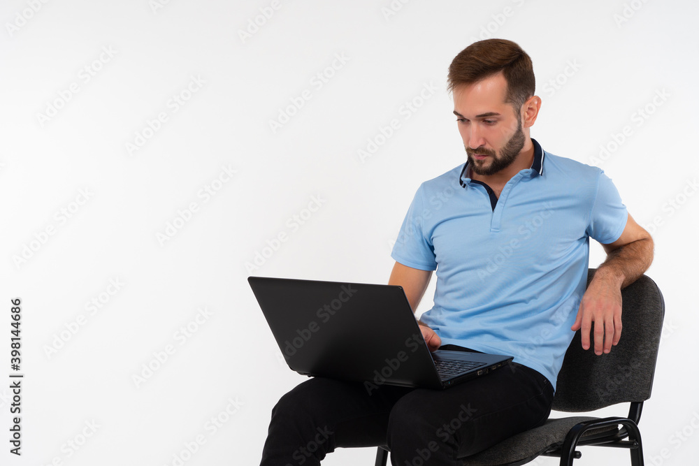Man in a polo holds a laptop. Young guy with a computer on his lap. Man with laptop on a white background. Portrait of a young businessman. Concept - he does business on Internet. IT businessman Man in a polo holds a laptop. Young guy with a computer on his lap. Man with laptop on a white background. Portrait of a young businessman. Concept - he does business on Internet. IT businessman