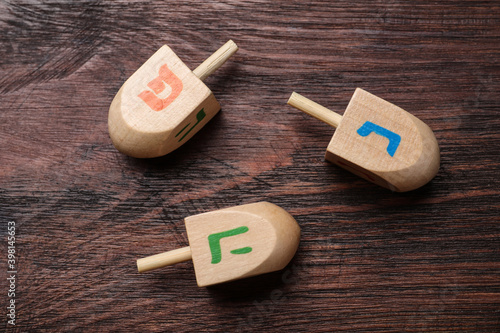 Hanukkah traditional dreidels with letters He, Pe and Nun on wooden table, flat lay photo