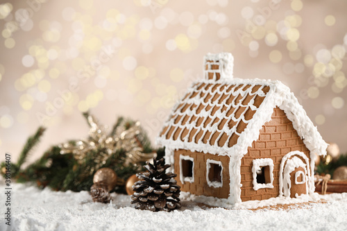 Beautiful gingerbread house decorated with icing on snow against blurred festive lights, space for text © New Africa