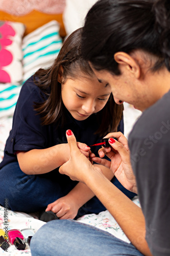 young man painting a little girl's nails red