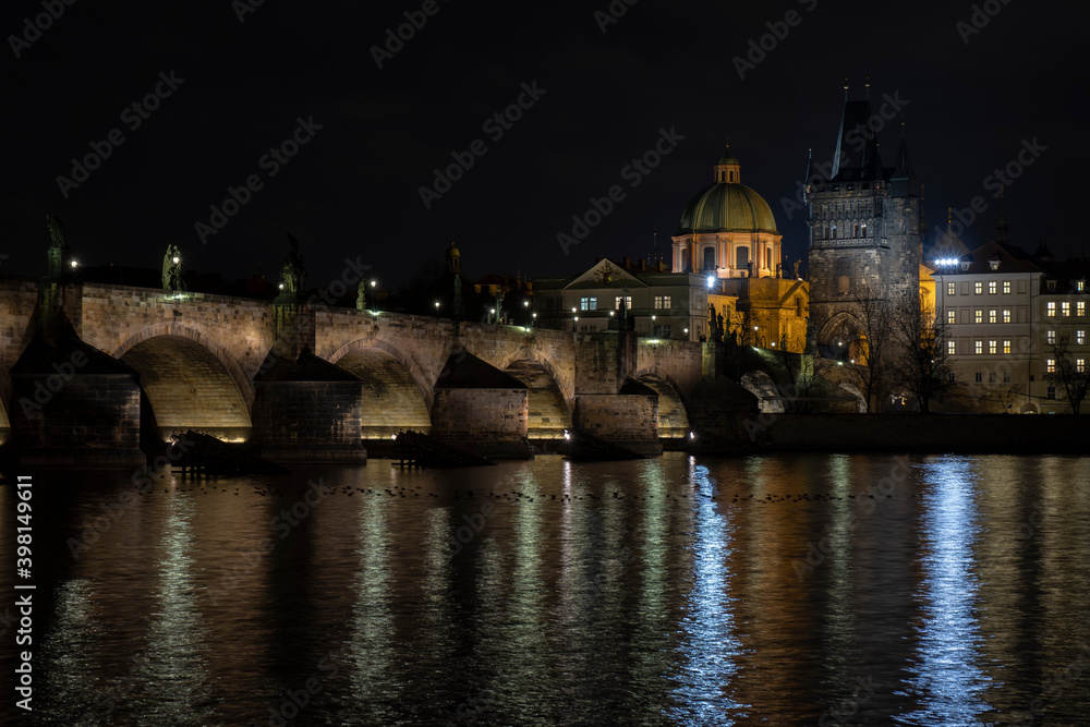 Fototapeta premium Charles Bridge and light from street lights in Prague and the level of the Vltava River after sunset in the Czech Republic