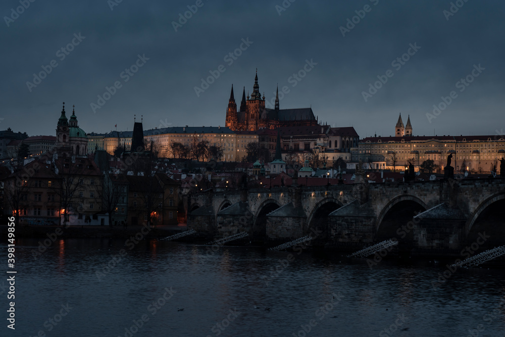 . prague castle and charles bridge and st. vita church lights from street lights are reflected on the surface of the vltava river in the center of prague at night in the czech republic