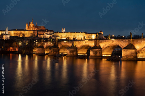 . prague castle and charles bridge and st. vita church lights from street lights are reflected on the surface of the vltava river in the center of prague at night in the czech republic