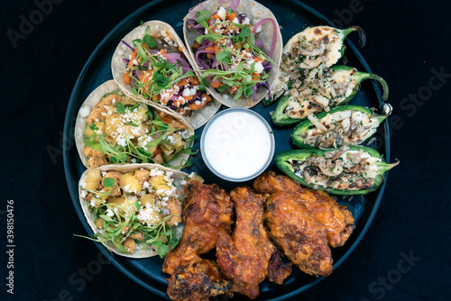 Fotografie Overhead view of delicious appetizer sampler plate with chicken and steak tacos, poppers, and buffalo wings makes the mouth water and the stomach growl